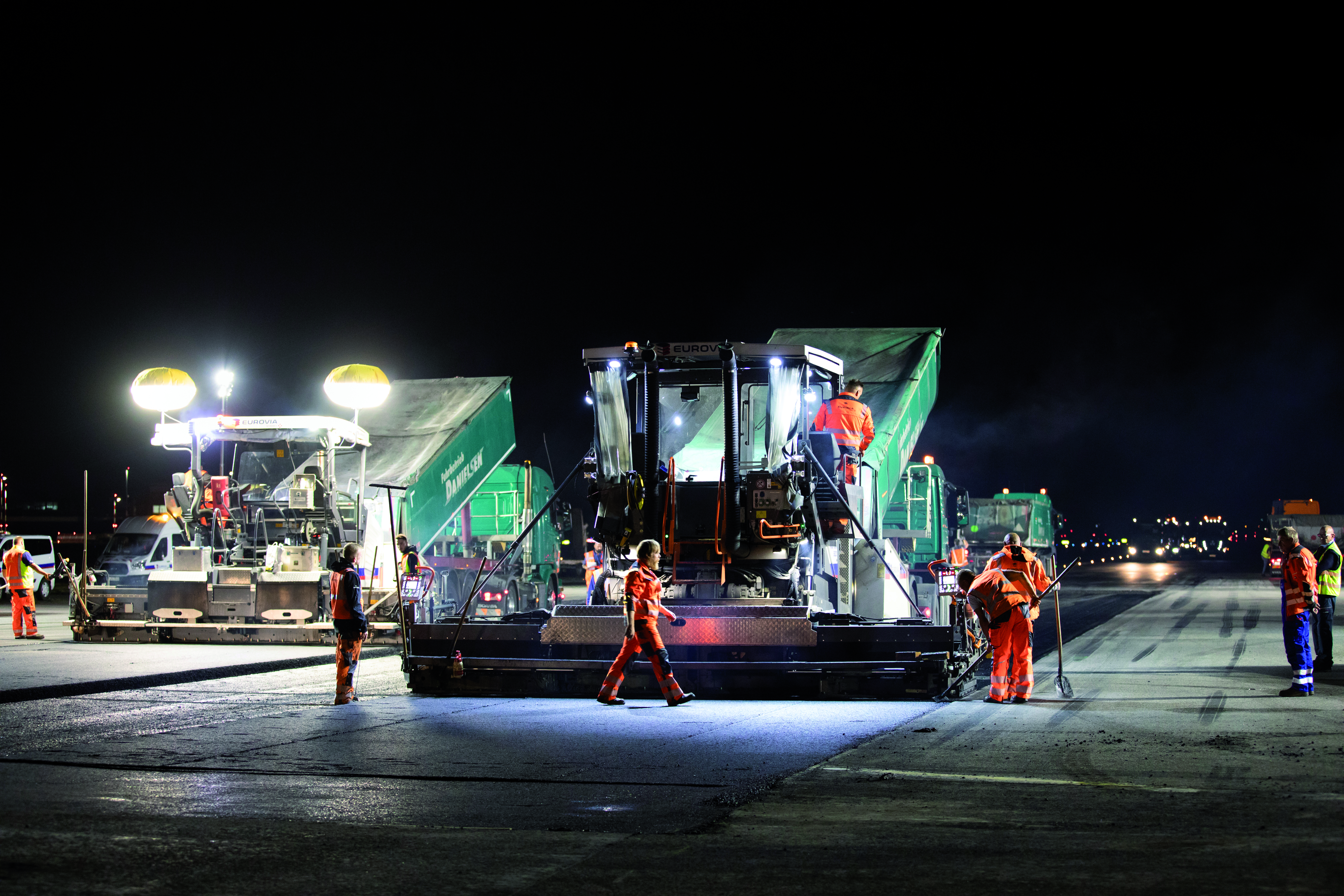 Nachtbaustelle: Bauarbeiter sanieren Straße bei Nacht.