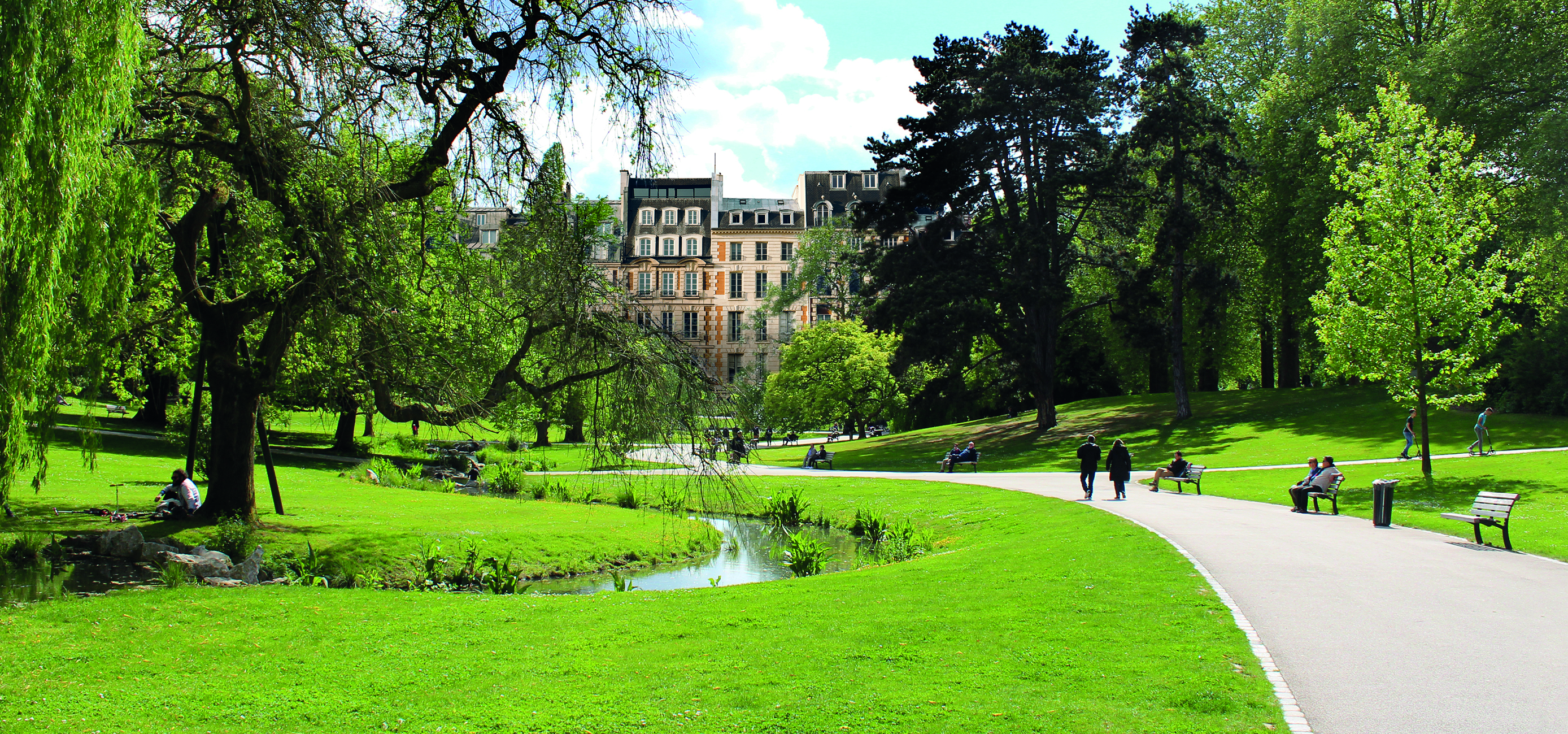 Park mit Spaziergängern und einem kleinen Bach.