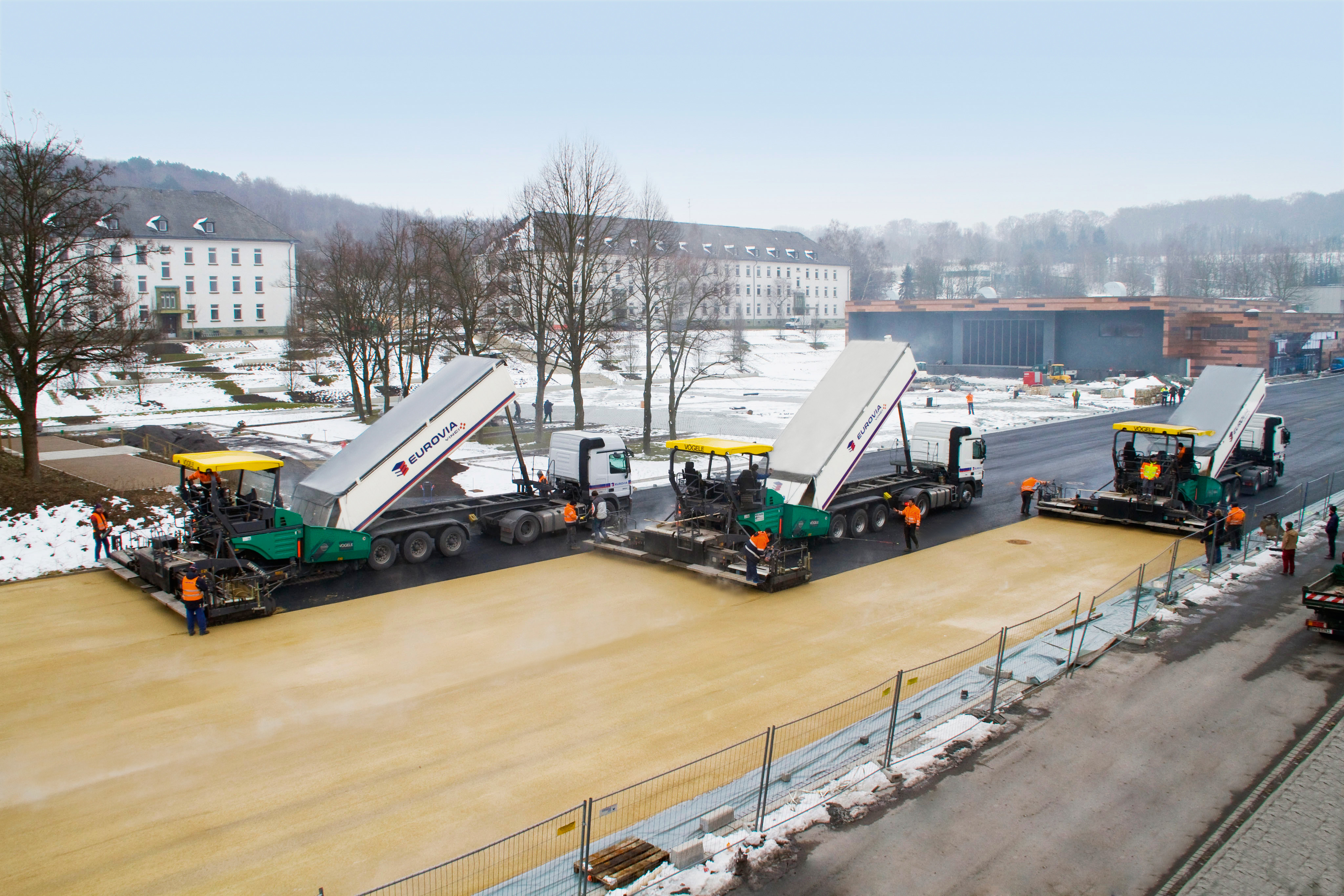 Bauarbeitende beim Einbau von farbigem Asphalt.