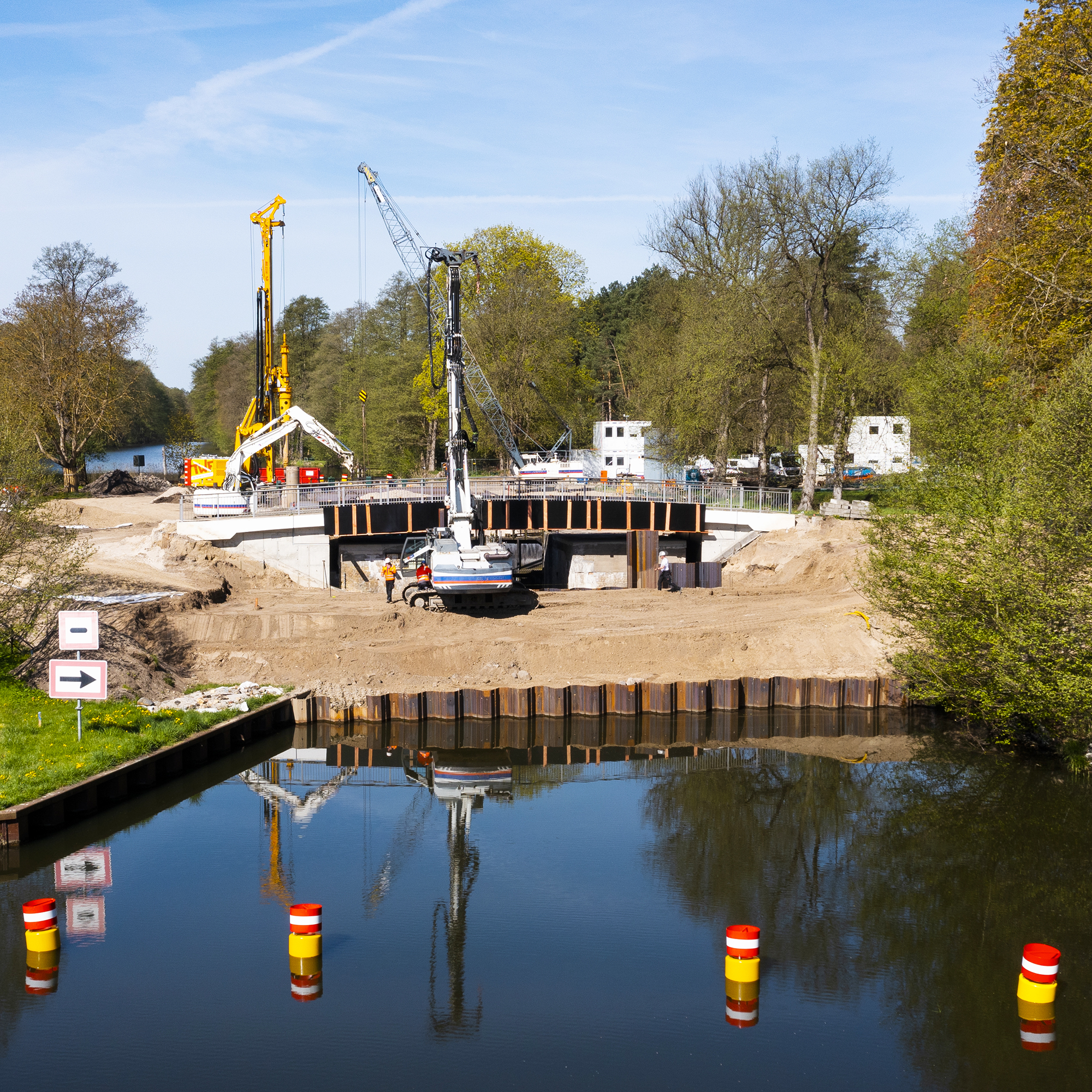 Kräne heben Baumaterialien auf einer Baustelle.