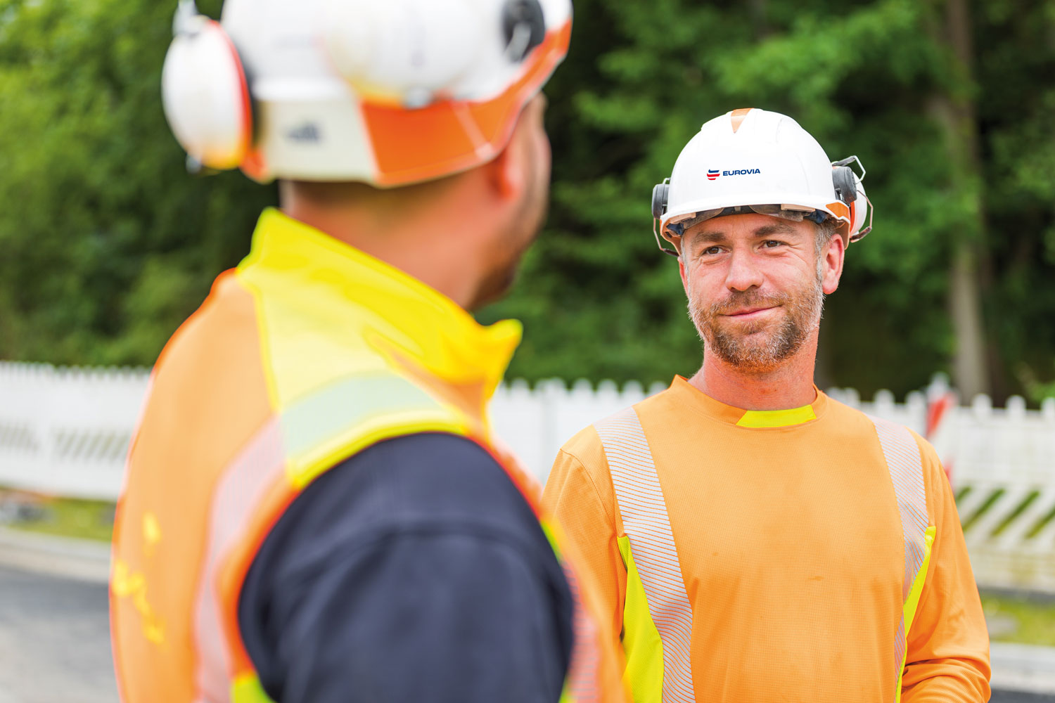 Ein Mann spricht mit einem anderen Mann, dessen Rücken zu sehen ist.
