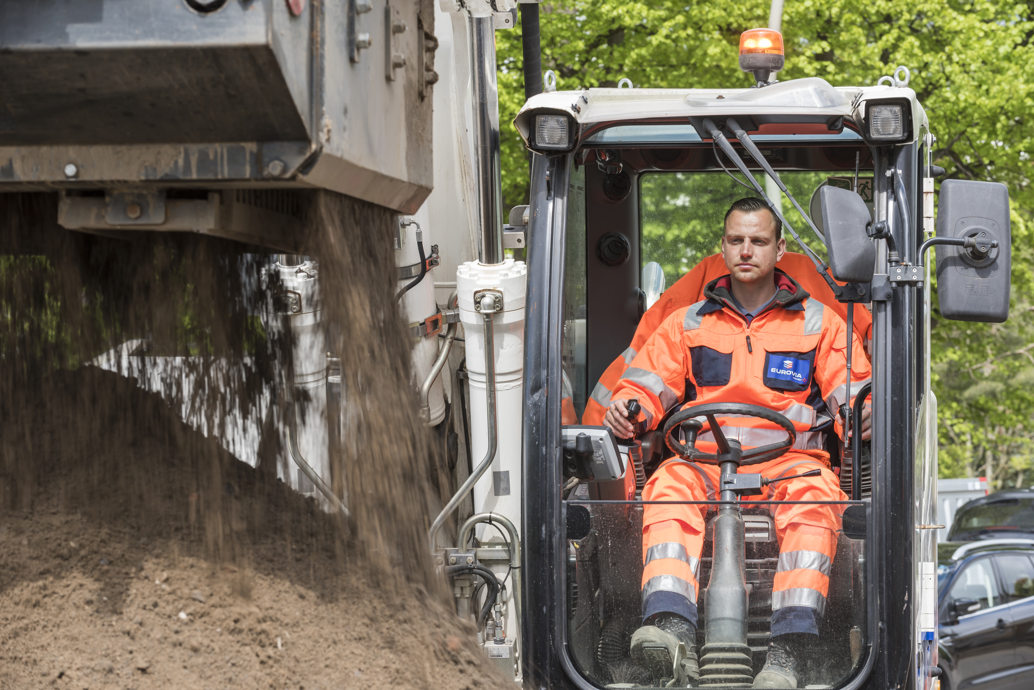 Mitarbeiter in PSA bedient einen Bagger, der Erde aushebt.