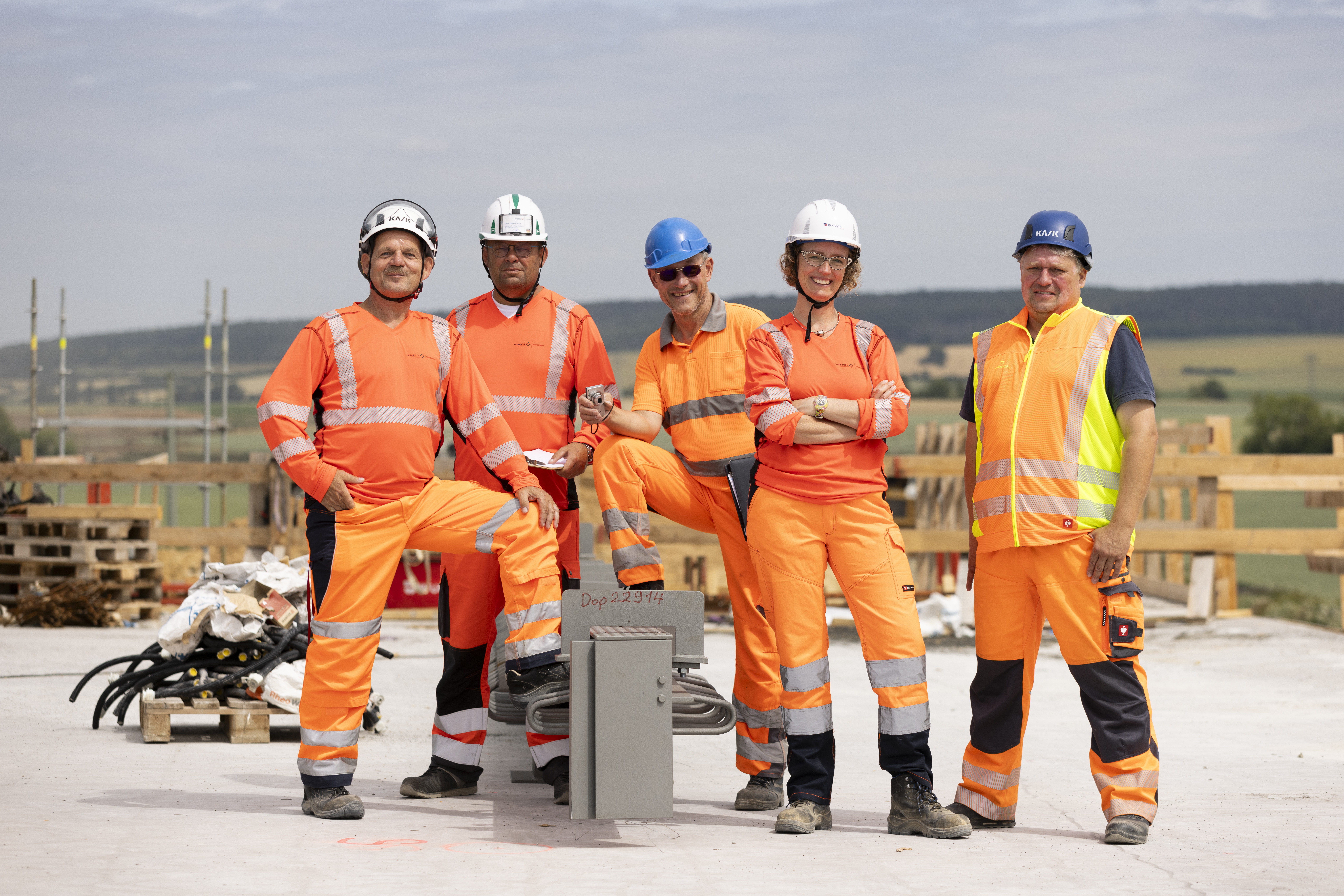 EUROVIA-Team, vier Männer und eine Frau, stehen vor einer Baustelle.