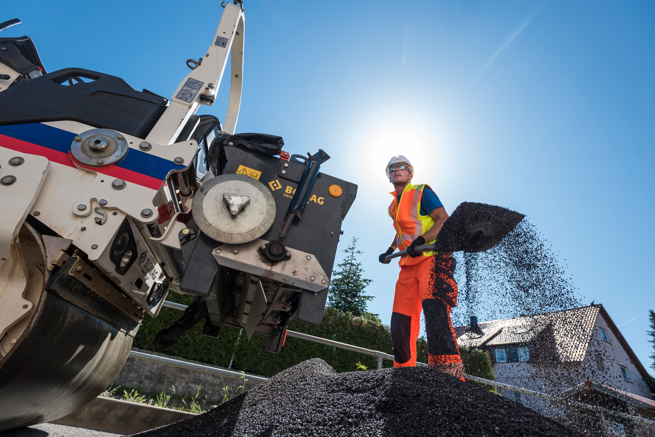 Bauarbeiter schaufelt Asphalt aus einem niedrigen Kamerawinkel.