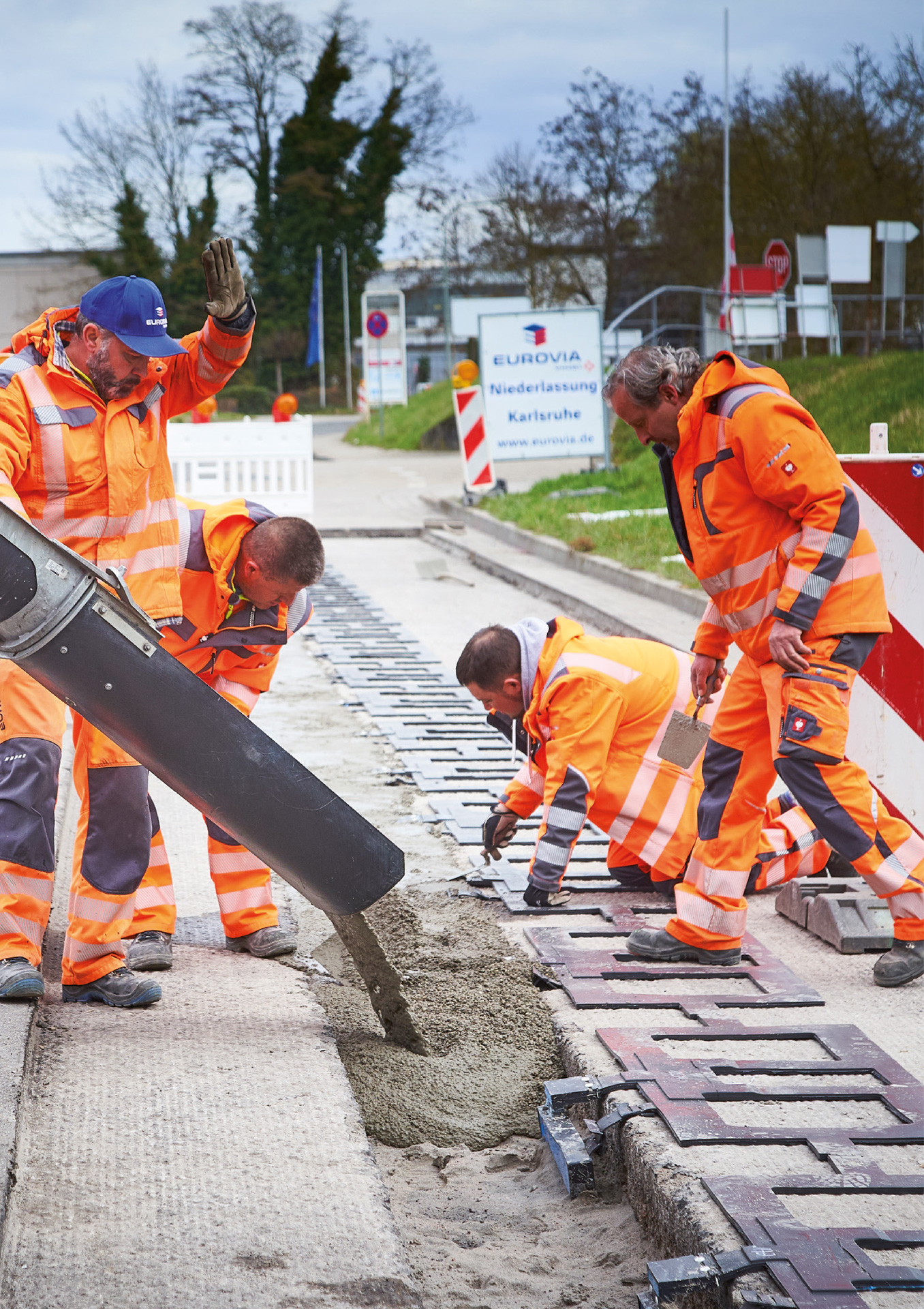 Vier Bauarbeiter in PSA füllen Zement in die Strecke. 