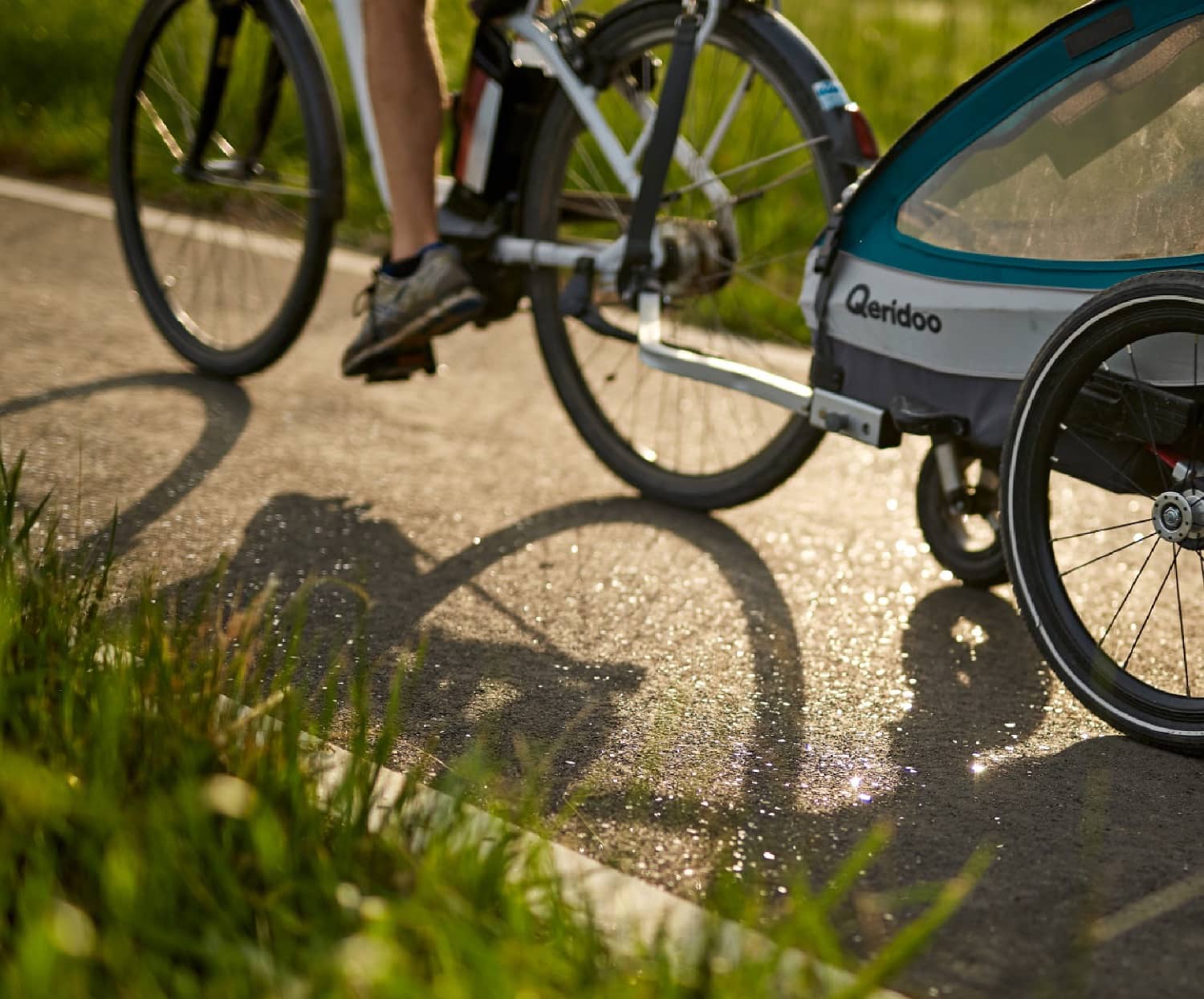 Hinterrad eines Fahrrads, das über eine Strecke mit eingebautem Lumivia-Asphalt fährt, der Boden glitzert im Tageslicht.