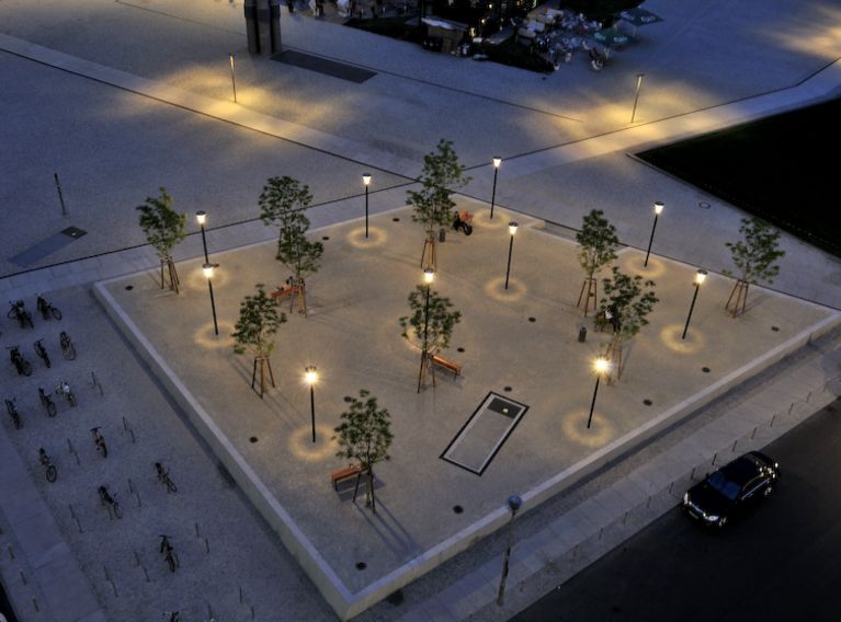 Parkanlage von oben, mit Lichtern, Bänken und einigen Bäumen.
